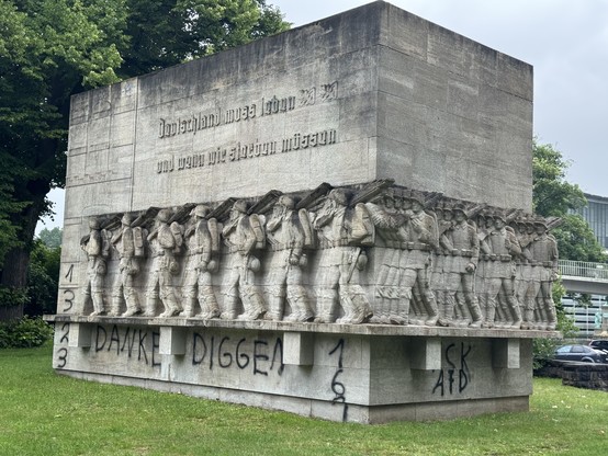 Ein großes Steindenkmal zeigt eine Reliefskulptur von Soldaten in Uniform, die Gewehre tragen. Der Text auf der Vorderseite lautet in deutscher Sprache: "Deutschland muss leben und wenn wir sterben müssen ."

Darunter hat jemand 161 und FCK AfD gesprüht 